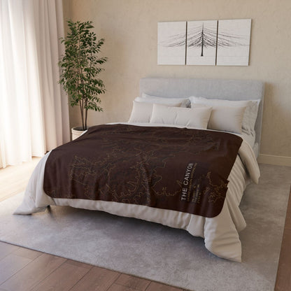 The Canyon Grand Canyon fleece blanket styled on a bed