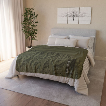 The Ridge Grand Teton topographic fleece blanket styled on a bed